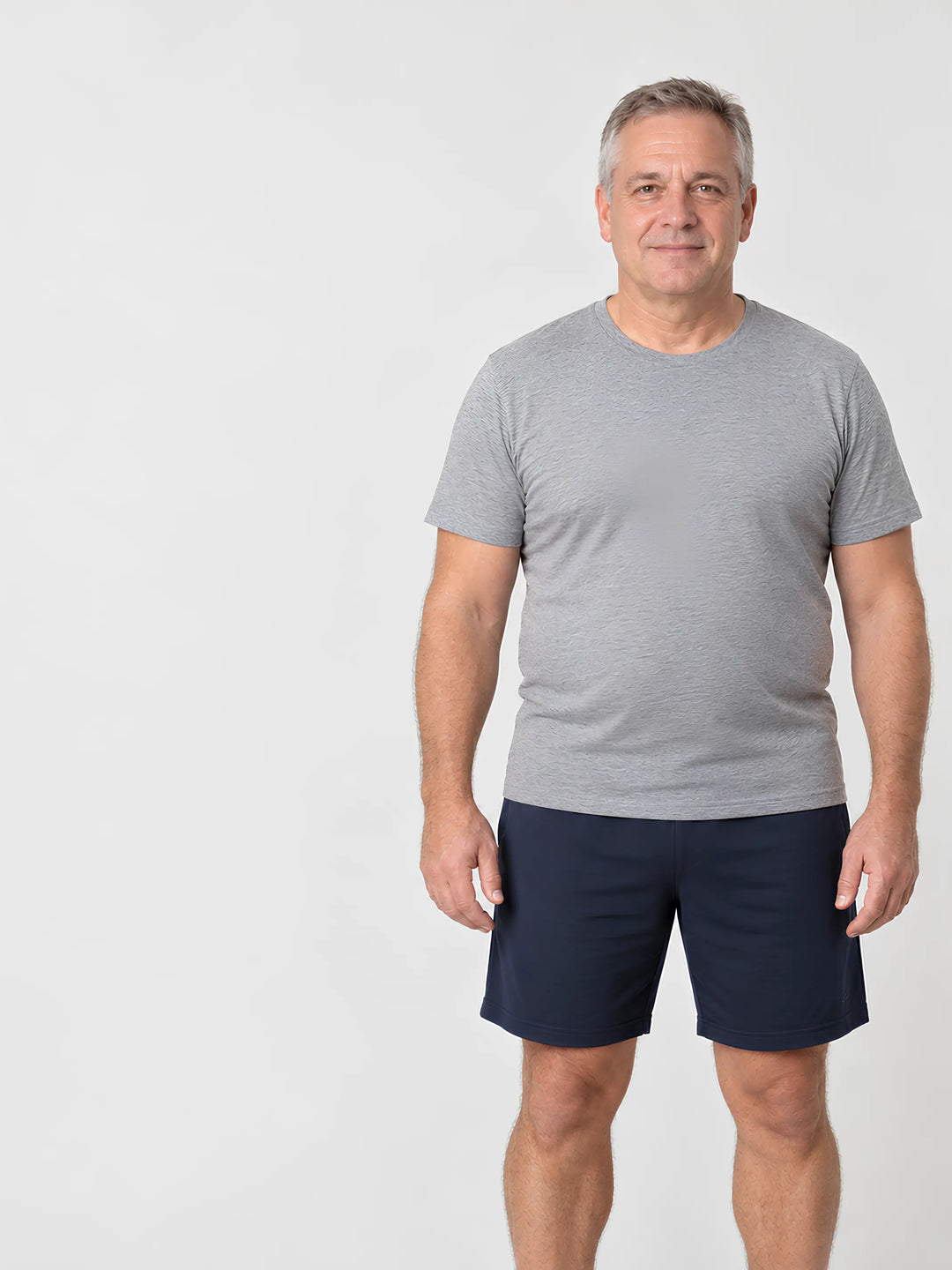 Man van middelbare leeftijd met een vollere lichaamsbouw, staand in grijs T-shirt en donkere short